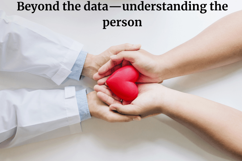 doctor supporting a patients hand holding a heart, representing the human element of care.